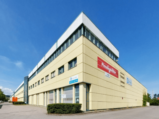 Beiges Industriegebäude mit "Pfennigpfeiffer"- und "Duisport"-Schildern, blauem Himmel.