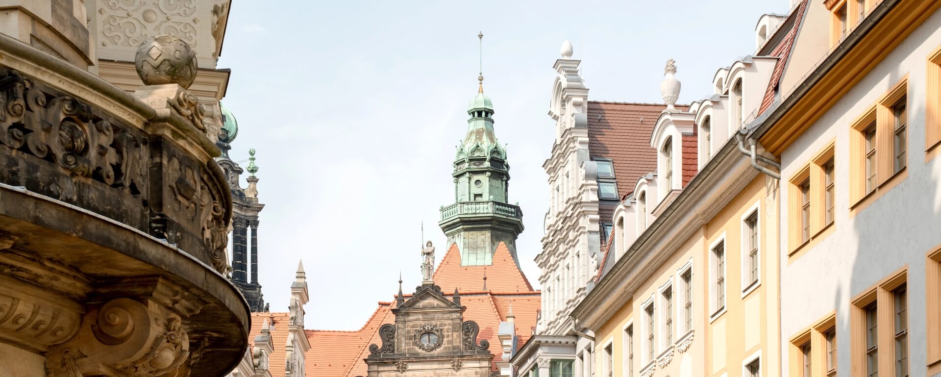 Historische Straßenszene in Dresden mit verzierter Architektur, grünem Kupfertürmchen und traditionellen Gebäuden.